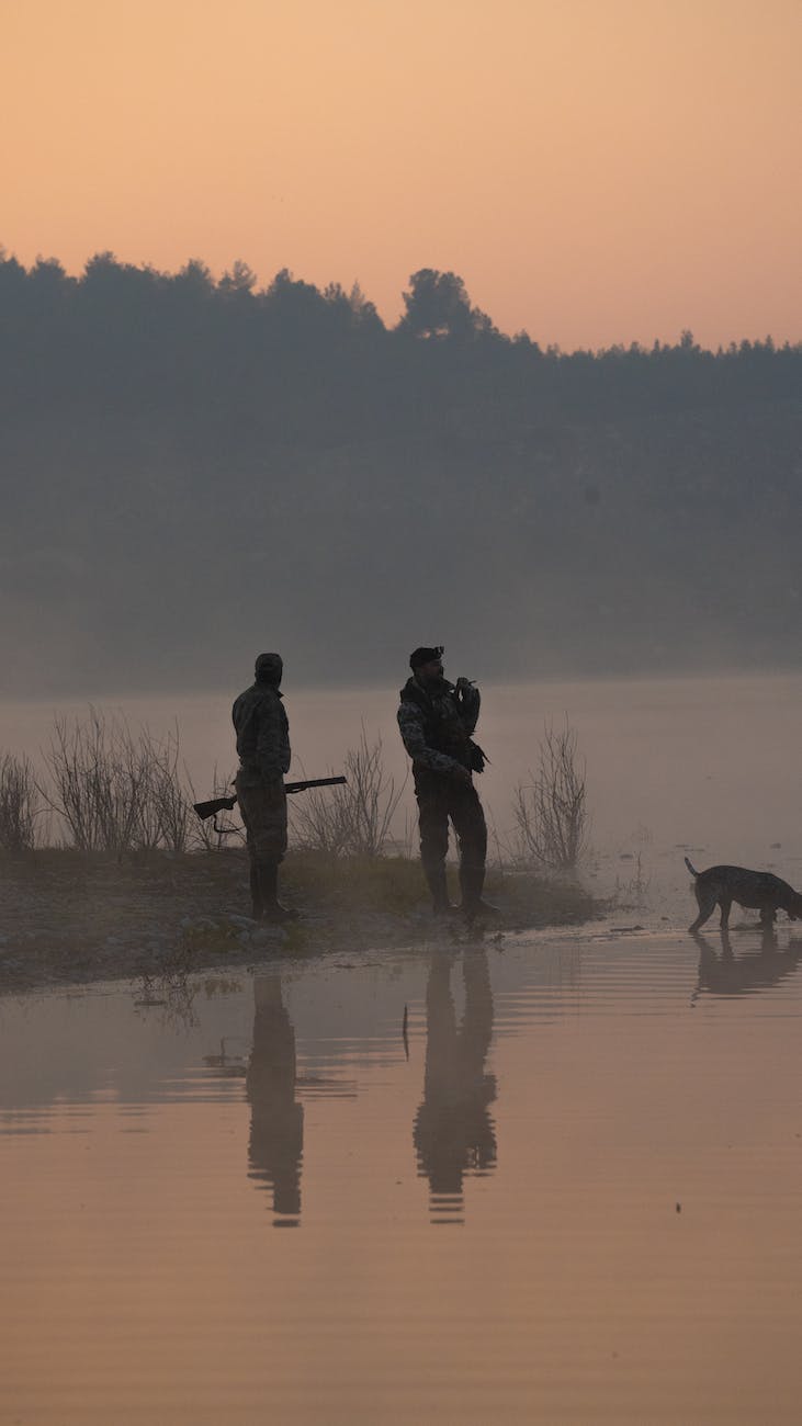 two people with a dog by a lake